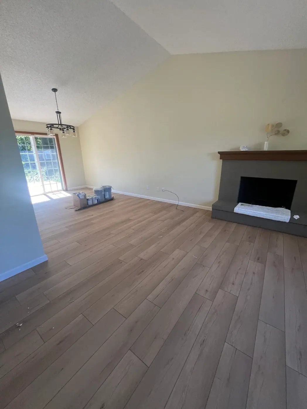 Living room with new wood-look plank flooring, freshly painted walls and a fireplace under a vaulted ceiling
