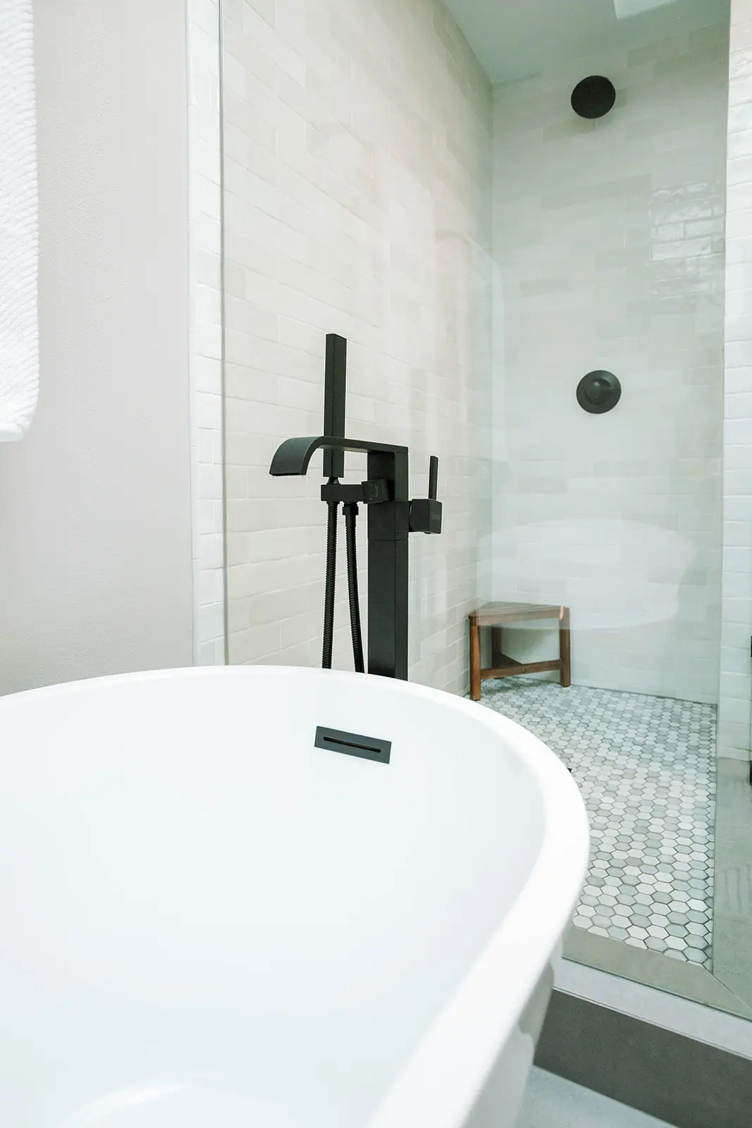 Freestanding tub with a matte black floor-mounted filler next to a glass walk-in shower