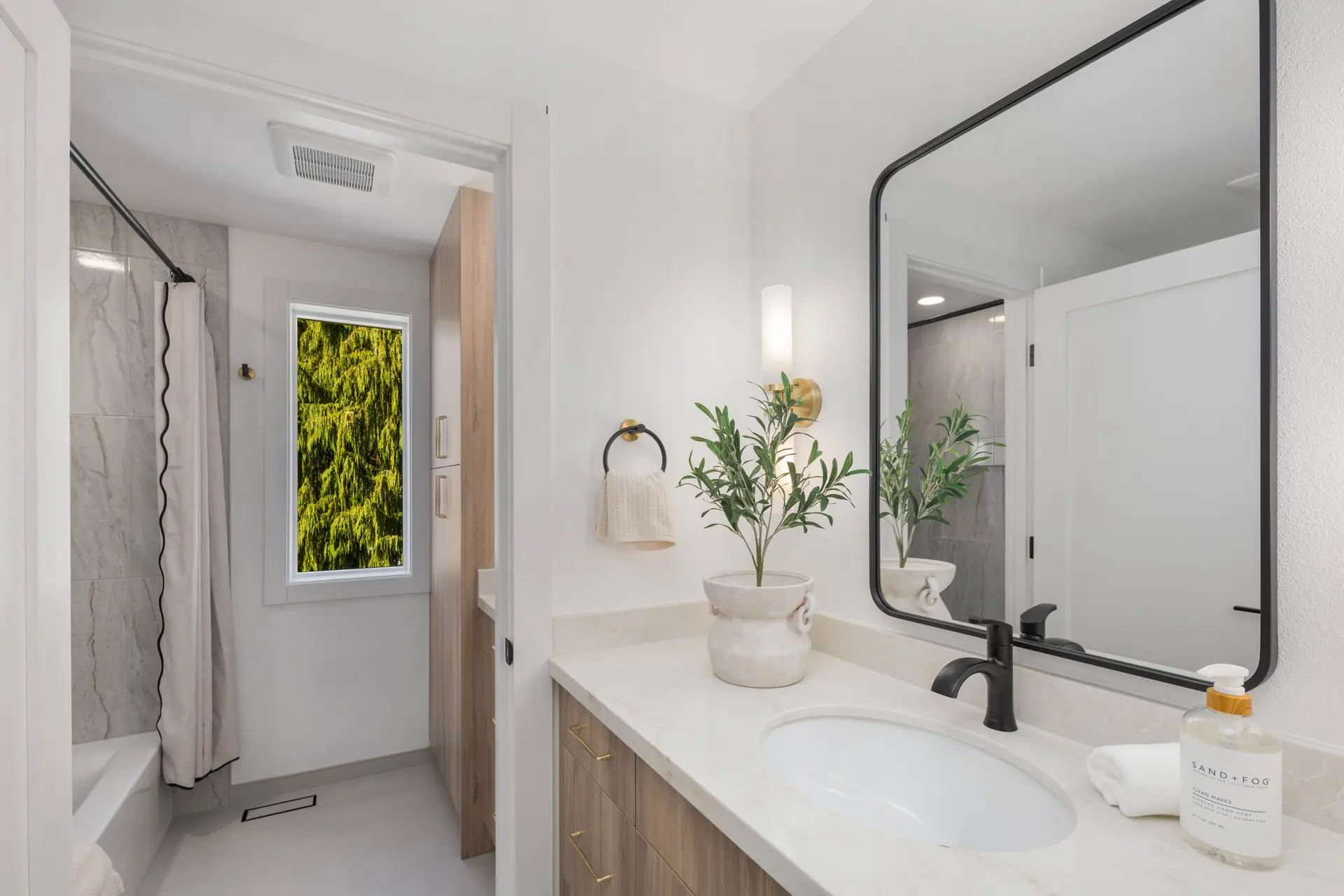Bathroom with a white-top vanity, black-framed mirror and tiled tub surround