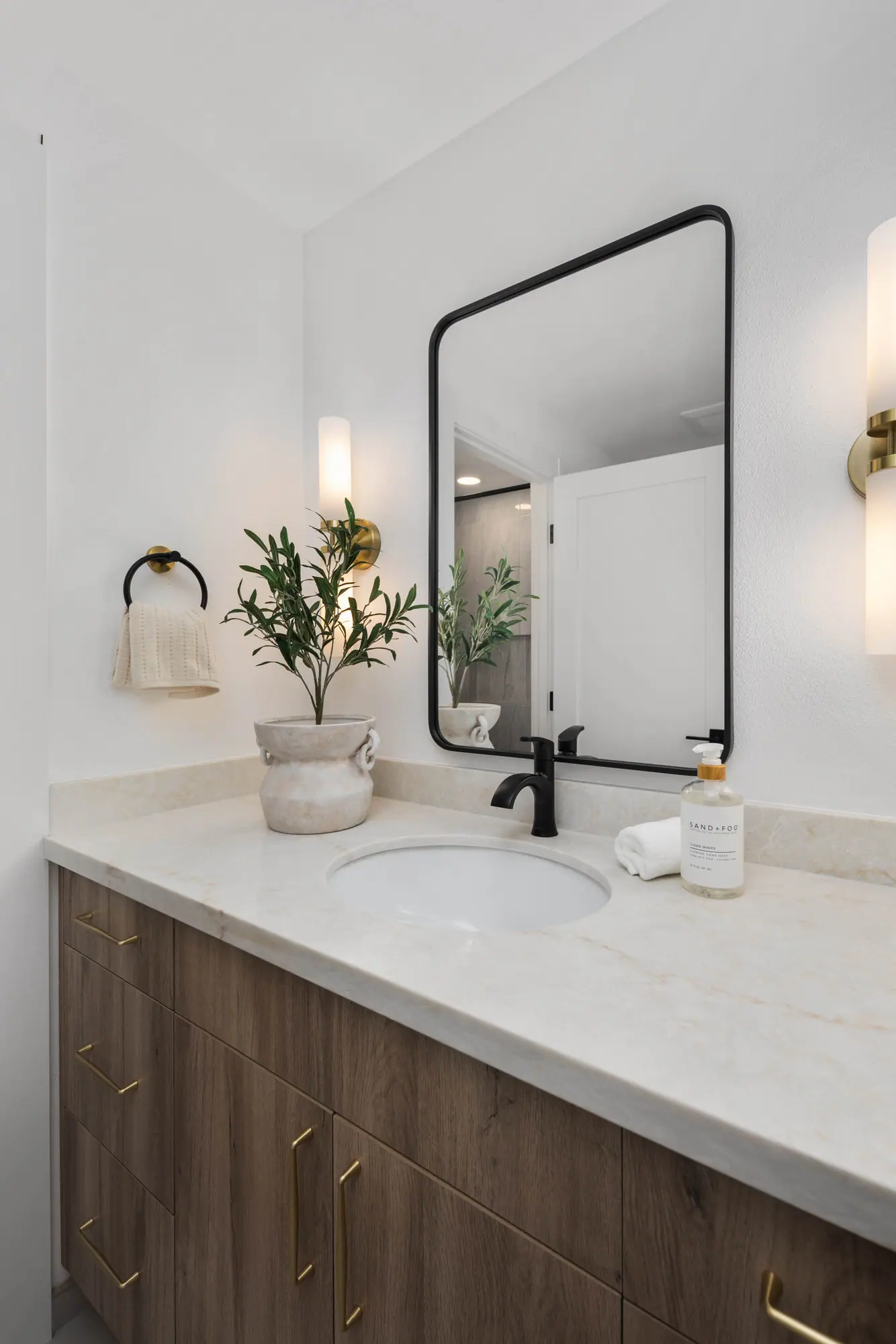Vanity with a dark wood cabinet, white countertop and black-framed mirror