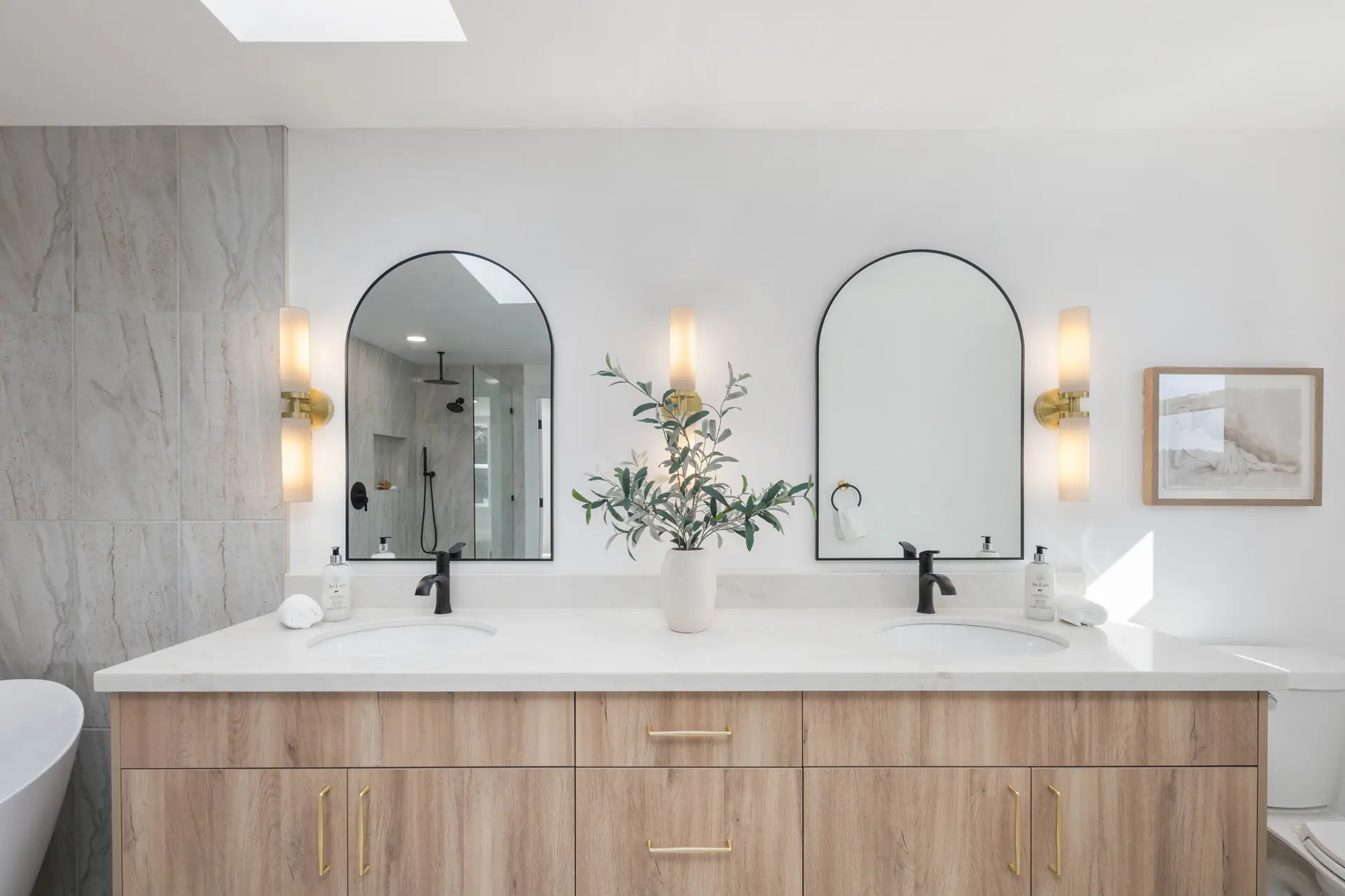 Double vanity with arched mirrors, wall sconces and matte black faucets