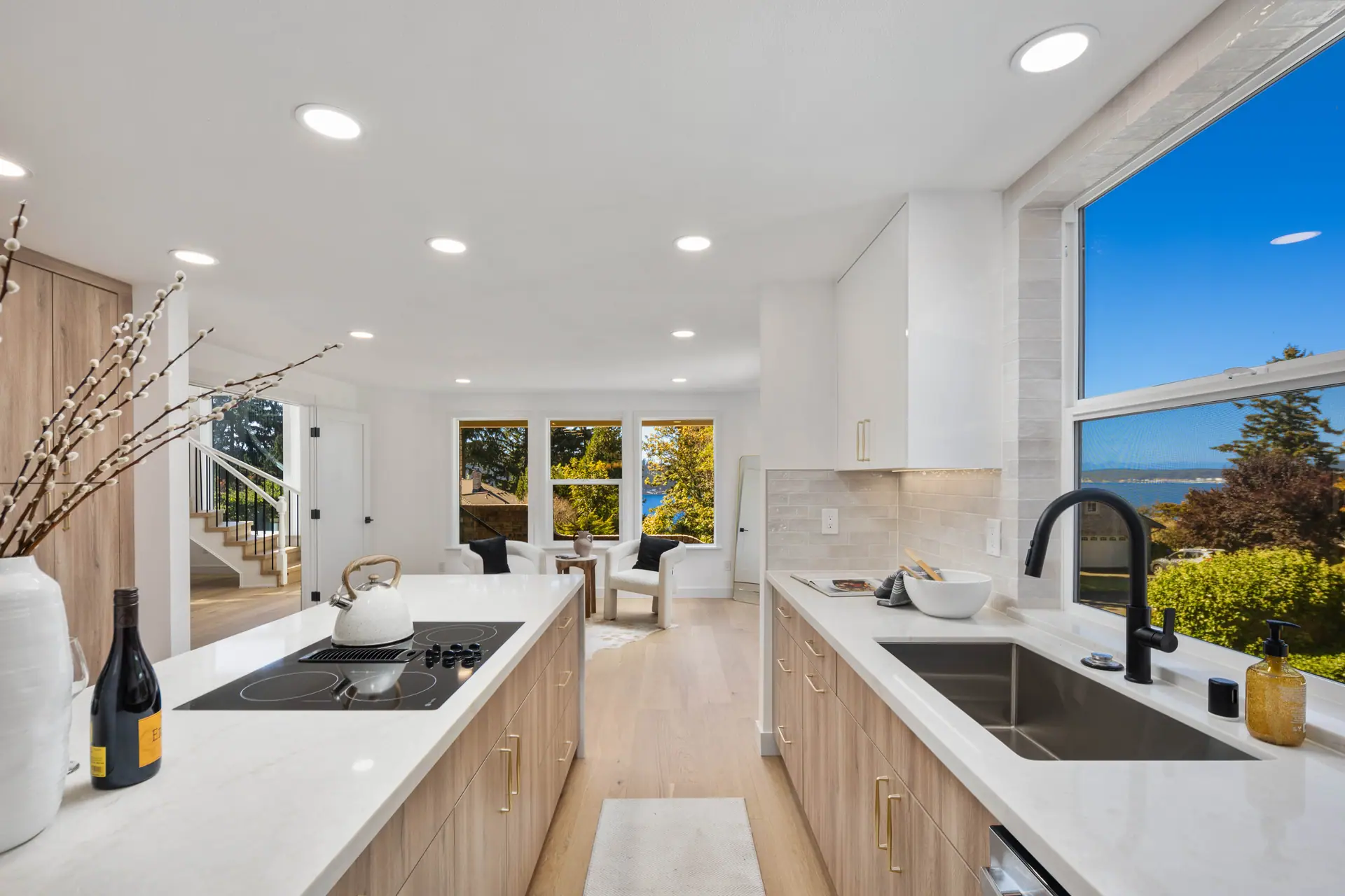 Remodeled kitchen with light wood cabinets, white countertops and a large window, open to the living area