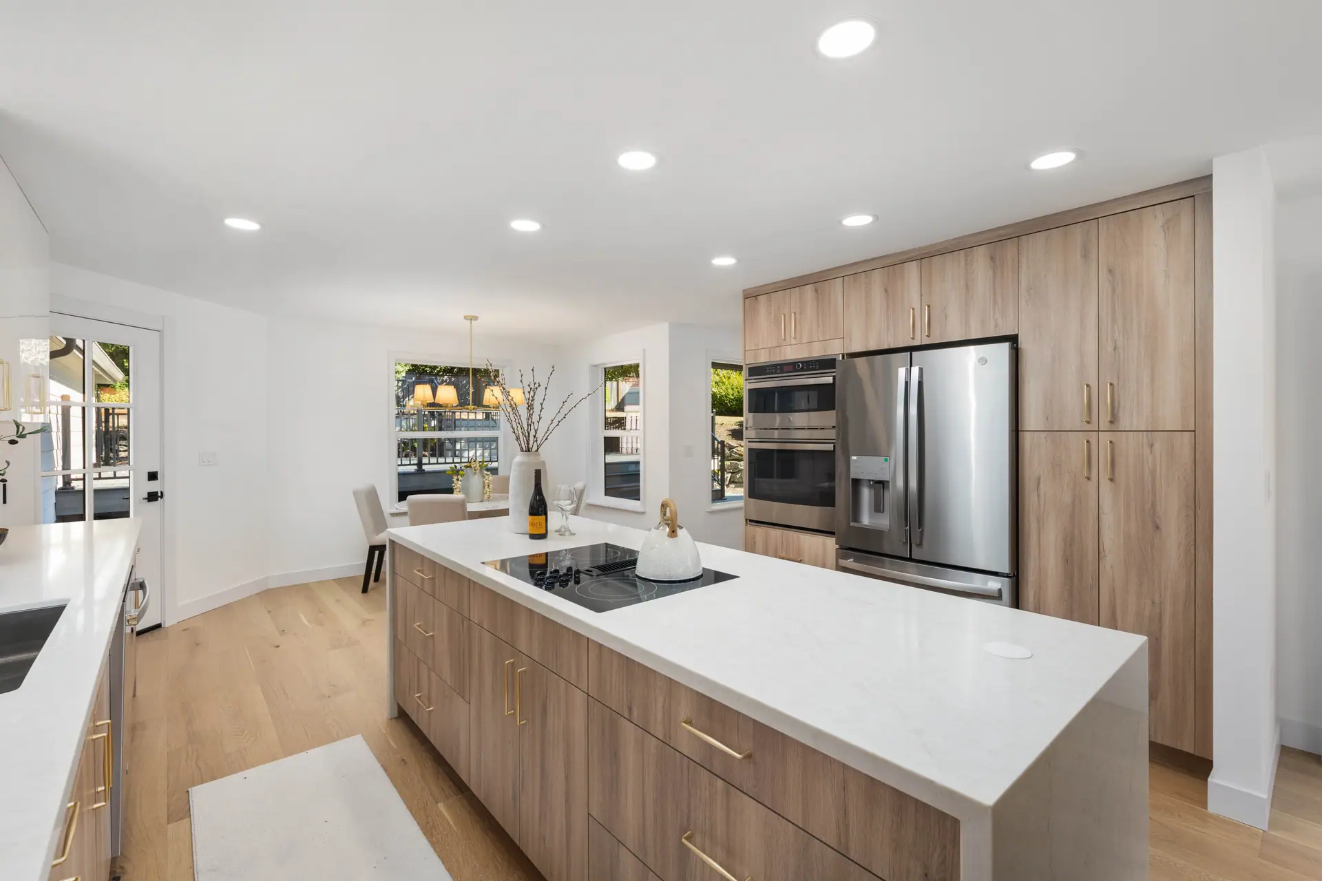 Kitchen island and tall light wood cabinets with built-in wall ovens and refrigerator
