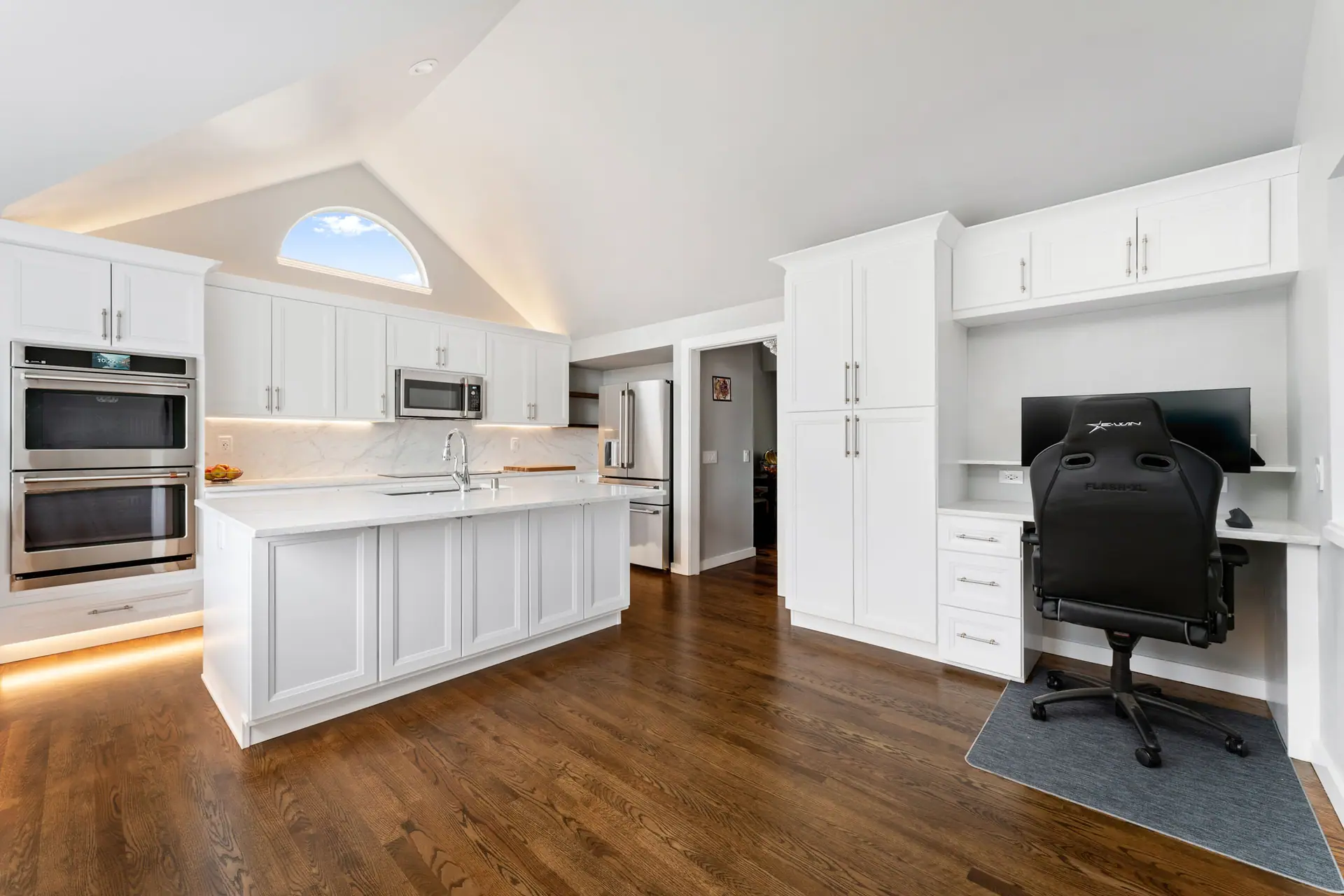 Kitchen island, double wall ovens and a built-in desk area with white cabinetry