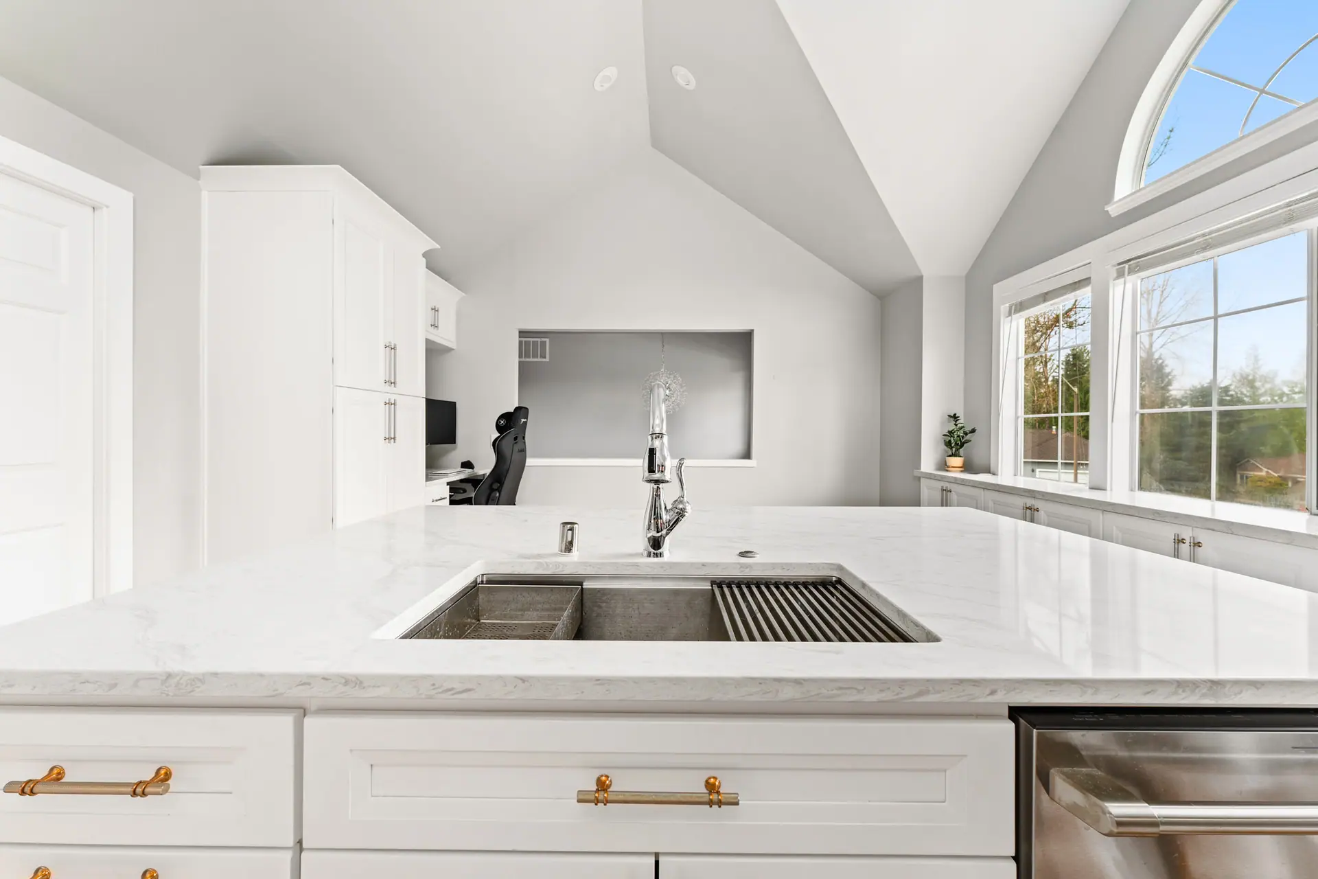 Island with a large undermount workstation sink and gold cabinet pulls