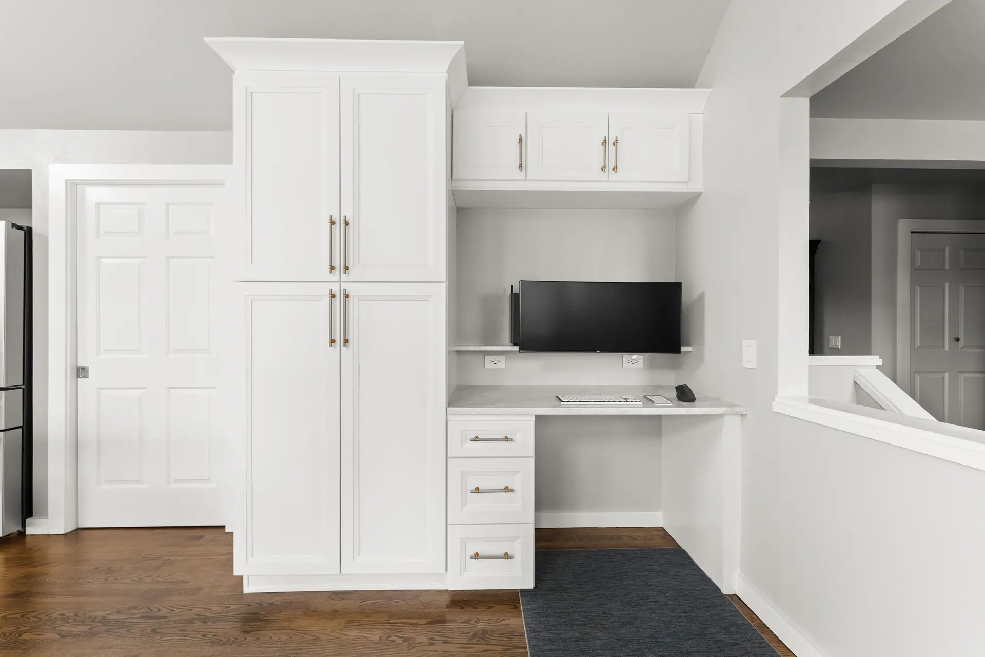 Tall white pantry cabinets beside a built-in desk nook