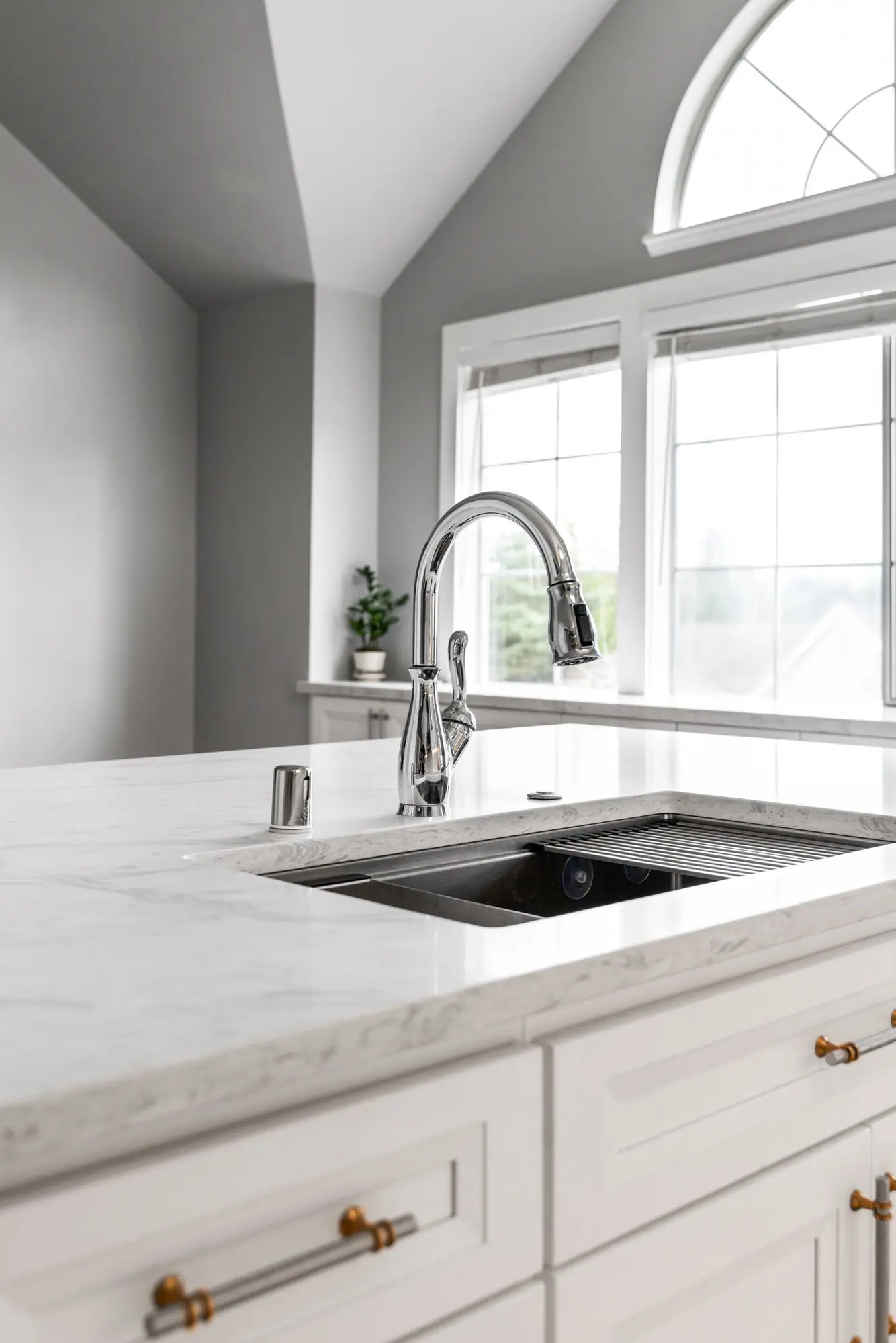 Undermount sink and faucet on a white island below arched windows