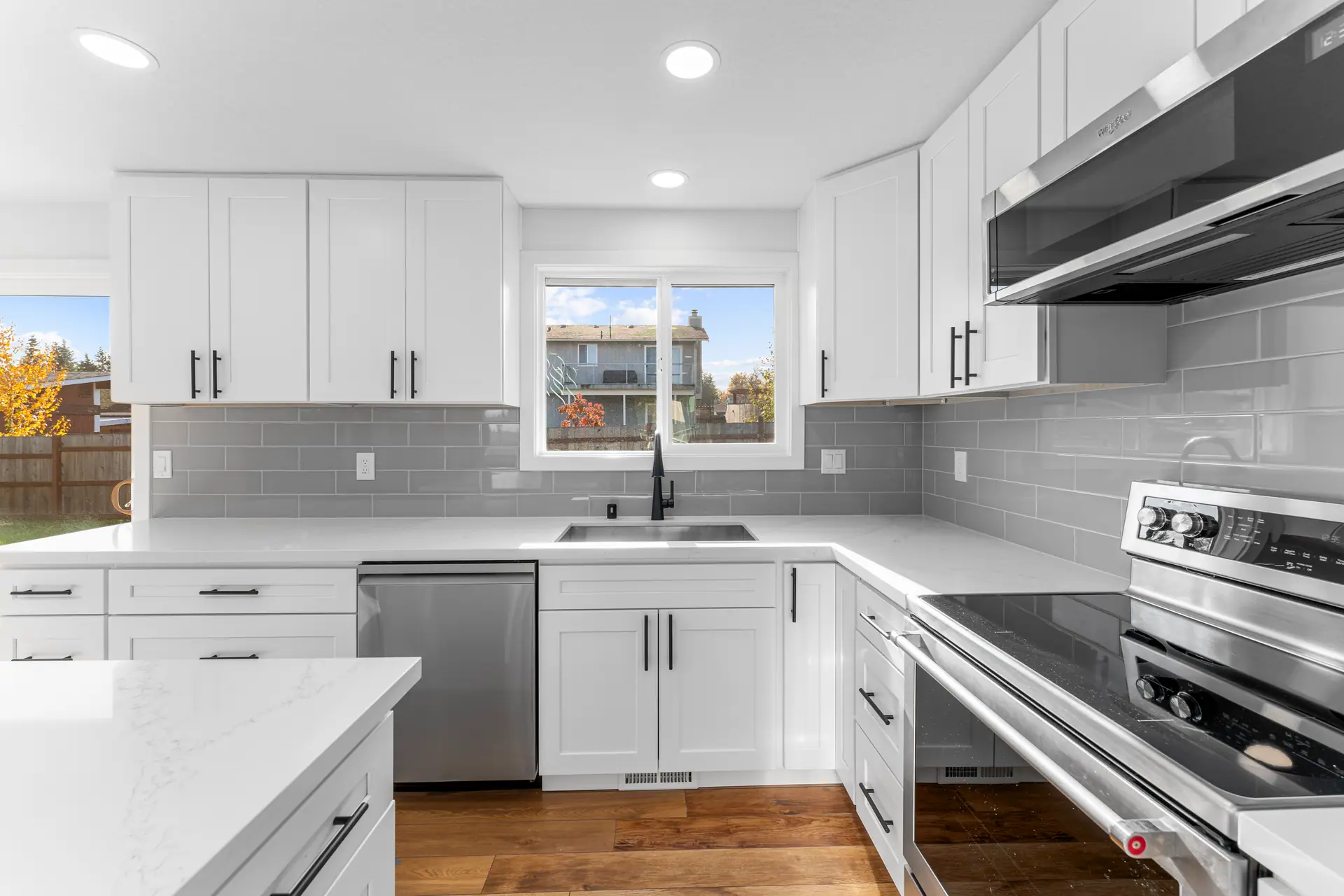 White shaker cabinets with a gray subway tile backsplash, stainless range and range hood