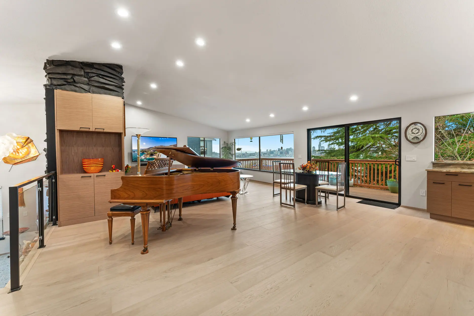 Open great room with light wood-look flooring, recessed lighting and wood built-ins