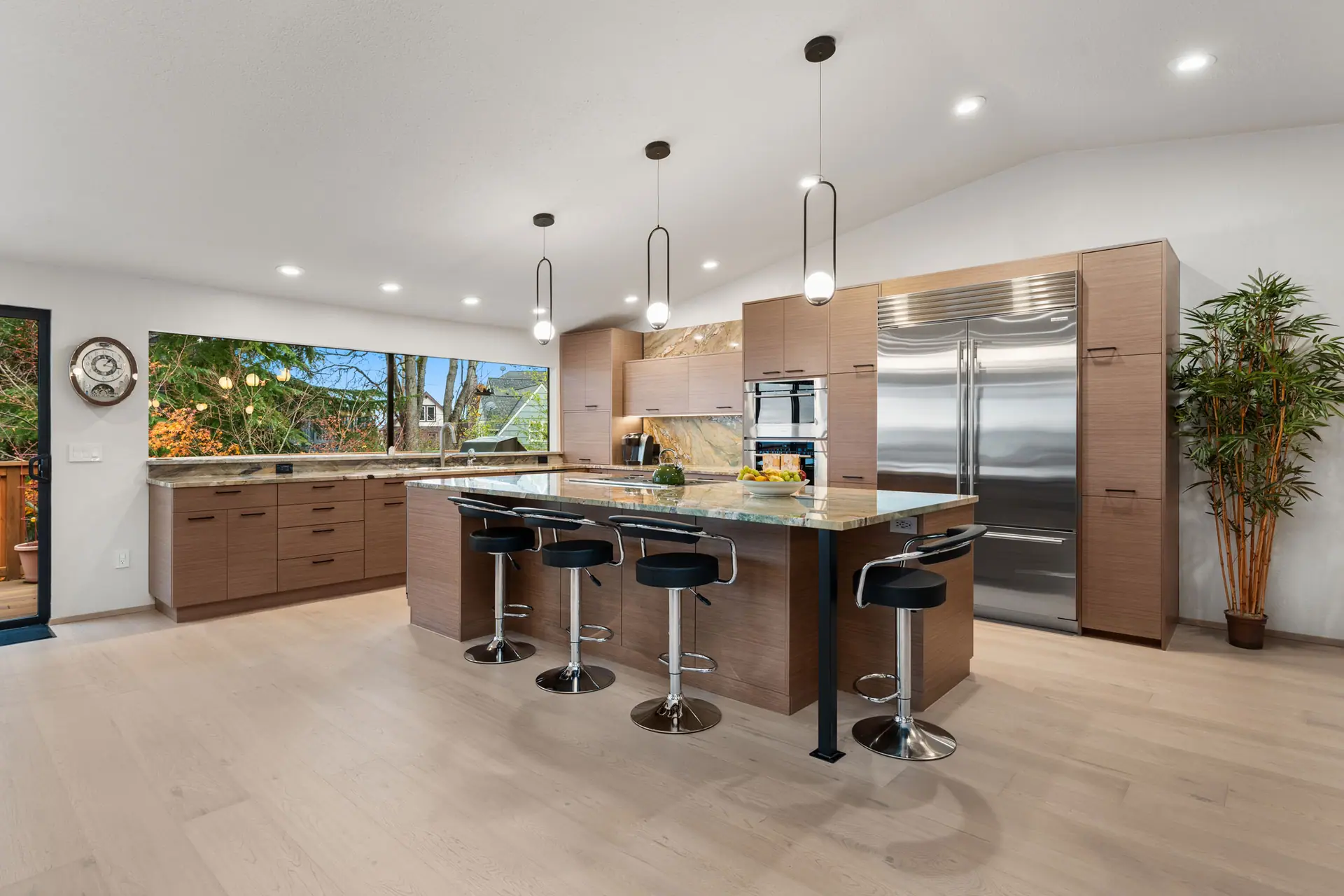 Open kitchen with wood cabinetry, a large island with seating, pendant lights and stainless appliances
